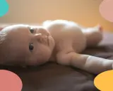 Un bebé de 2 meses, con ojos curiosos, yace boca arriba. Parece que este pequeño no duerme, ¡sus ojitos están bien abiertos!