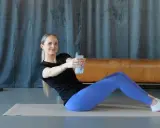 Frau macht isometrisches Krafttraining mit einer Wasserflasche, trainiert den Rumpf und die Bauchmuskeln.