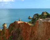 Zwei Wanderer genießen die milden Temperaturen Portugals im November an einer Klippe mit Blick auf das Meer.