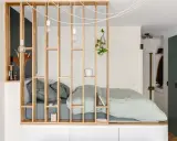 Aménagement astucieux d'un studio T2 avec un lit douillet séparé par une étagère en bois.