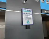 Taxi Melkior-skylt vid lgg flygplats. En övervakningskamera är monterad under skylten.