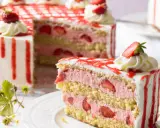 Eine moderne Erdbeertorte mit drei Schichten Biskuit, Erdbeercreme und frischen Erdbeeren, verziert mit Sahnetupfern und rotem Zuckerguss.