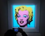 A person photographs Andy Warhol's iconic Marilyn Monroe printmaking, capturing the vibrant colors and pop art style.