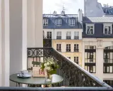 Petit-déjeuner sur le balcon avec vue sur les toits de Paris. Une tasse de café, un livre "Paris mon amour" et des fleurs, un moment de détente au saint-grégoire.