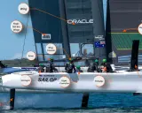 Ein Team beim Katamaran fahren. Die Crew steuert das Boot mit einer großen Flügel-Segelkonstruktion, während die Foils für Auftrieb sorgen.