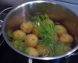 En gryta med dillkokt potatis i vatten. Snart redo att serveras med smör och mer dill.