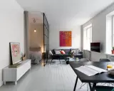 Smart lösning för att bo på liten yta. Sovrummet avskiljs med en glasvägg. Vardagsrummet har en soffa och ett soffbord.