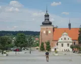 Włocławek stare miasto: plac z kościołem, wieżą i ludźmi spacerującymi w słoneczny dzień.