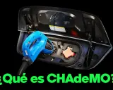 Un conector CHAdeMO azul se inserta en el puerto de carga de un coche eléctrico.