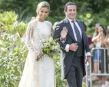 Novia y novio sonríen en la boda de María Pombo. Ella lleva un vestido blanco con encaje y él un traje gris.