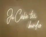 Neonowy napis "Ja ciebie też bardzo" rozświetla ścianę, tworząc ciepłą atmosferę.
