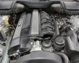 Silnik BMW E39, prawdopodobnie V8, z widocznym kolektorem dolotowym i osłoną zaworów z napisem BMW.