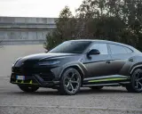 Un imponente **lamborghini urus negro** se exhibe con detalles en verde lima, posado sobre un camino empedrado.