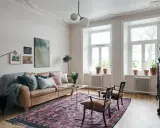 En vardagsrumsinredning som visar vad bohemisk betyder: en brun skinnsoffa, en stor mönstrad matta, konst och växter.