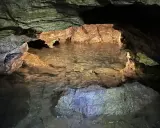 Wnętrze jaskini Radochowskiej z krystalicznie czystą wodą odbijającą skalne ściany.
