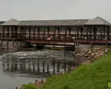Drewniany most nad rzeką, jedna z atrakcji Supraśla. Woda spływa kaskadą, tworząc pianę.