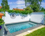 Petite piscine bleue dans un jardin verdoyant, décorée d'art mural. Un projet de permis de construire piscine réussi.