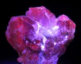 Cristallo rosso intenso, illuminato da luce viola, che fa pensare a qual è la pietra più preziosa al mondo.