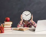 Dziecko z zegarem zamiast twarzy, stos książek, jabłko i laptop. Sierpień godziny pracy, nauka i przygotowania do szkoły.