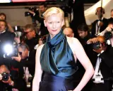 Tilda Swinton poses on the red carpet, surrounded by flashing cameras and eager photographers.