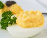 Zwei appetitliche russische Eier traditionell, gefüllt mit einer cremigen Eigelbmasse und garniert mit Petersilie.