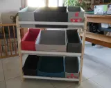 Étagère en bois avec des bacs de rangement pour jouets, dont un décoré d'un chat super-héros. Idéal pour fabriquer un rangement jouet organisé.