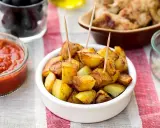 Patatas bravas dorées, servies avec une sauce tomate épicée et des olives. Un délice pour l'apéro !