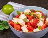 Erfrischender Wassermelonen-Feta-Salat mit Minze und Pinienkernen, garniert mit Limettenabrieb. Perfekt für heiße Tage.