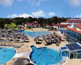 Słoneczny aquapark nad morzem z basenami, zjeżdżalniami i leżakami pod parasolami.