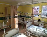 Szpitalna sala z łóżkami i aparaturą ortopedyczną.