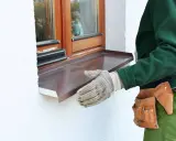 Instalación de un vierteaguas metálico en una ventana. El vierteaguas protege la pared de la lluvia.