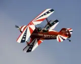 Rotes Pitts Special Doppeldeckerflugzeug mit Sternenmuster fliegt im blauen Himmel.