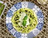 Deliciosa pasta con pesto, ideal para tus recetas de pasta con pesto. Servida en un plato decorado con un toque mediterráneo.