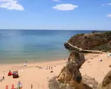 Sonniger Lagos Strand mit goldenem Sand, türkisfarbenem Wasser und Felsformationen. Menschen entspannen sich, spielen und genießen die Aussicht.