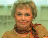Uśmiechnięta Joanna Chmielewska, autorka kultowych powieści kryminalnych, w beżowym swetrze i kolorowym szalu.