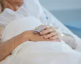 Mani di anziano con pulsossimetro, per monitorare la salute e valutare cosa mettere sulle piaghe da decubito.