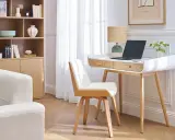 Un coin teletravail lumineux avec bureau blanc et bois, ordinateur portable, lampe et plante. Une étagère en bois et un canapé clair complètent l'espace.