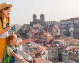 Una madre y su hija disfrutan de las vistas de Oporto con niños, señalando la ciudad histórica.