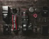 Zestaw fotograficzny: aparat Canon EOS 6D Mark II z obiektywem, lampa błyskowa, baterie i akcesoria. Podstawa aparatu fotograficznego gotowa do pracy.