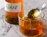 Sirope de agave en un vaso, con una cuchara vertiendo más. Ideal para endulzar recetas durante el embarazo.