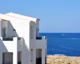 Maison blanche avec balcons face à la mer bleue. Idéal pour un dédommagement location saisonnière.