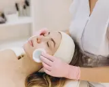 Una donna riceve una pulizia del viso con dischetti di cotone. La durata di una pulizia del viso varia, ma questo momento di relax è prezioso.