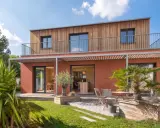 Maison moderne avec bardage bois et façade ocre. Idéal pour un conseil construction maison, avec jardin verdoyant et terrasse accueillante.