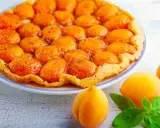 Découvrez les meilleures tartes aux fruits : une tarte tatin aux abricots dorés et caramélisés, garnie de fruits frais et de feuilles de basilic.