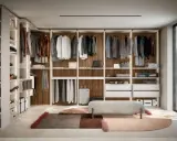 Ein moderner, offener Kleiderschrank, der zum Selberbauen inspiriert. Hängende Kleidung, Regale mit Accessoires und eine Sitzbank.