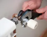 Manos ajustando llave de radiador con llave inglesa para cambiarla y evitar goteos.
