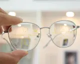 Dłoń trzyma okulary z oznaczeniami R i L. Na soczewkach widoczne są linie i cyfry, co sugeruje, że to okulary progresywne co to jest i jak działają.