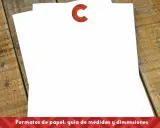 Dos hojas de papel blanco apiladas sobre una mesa de madera rústica. El papel para flyers está listo para ser diseñado.