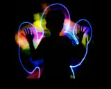 Silueta de niño jugando con light painting, creando auras de colores vibrantes a su alrededor.