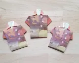 Drei gefaltete Euro-Scheine in Form von Hemden liegen auf einem Holztisch. Das kunstvolle Falten von Geld zu kleinen Hemden ist eine kreative Idee.